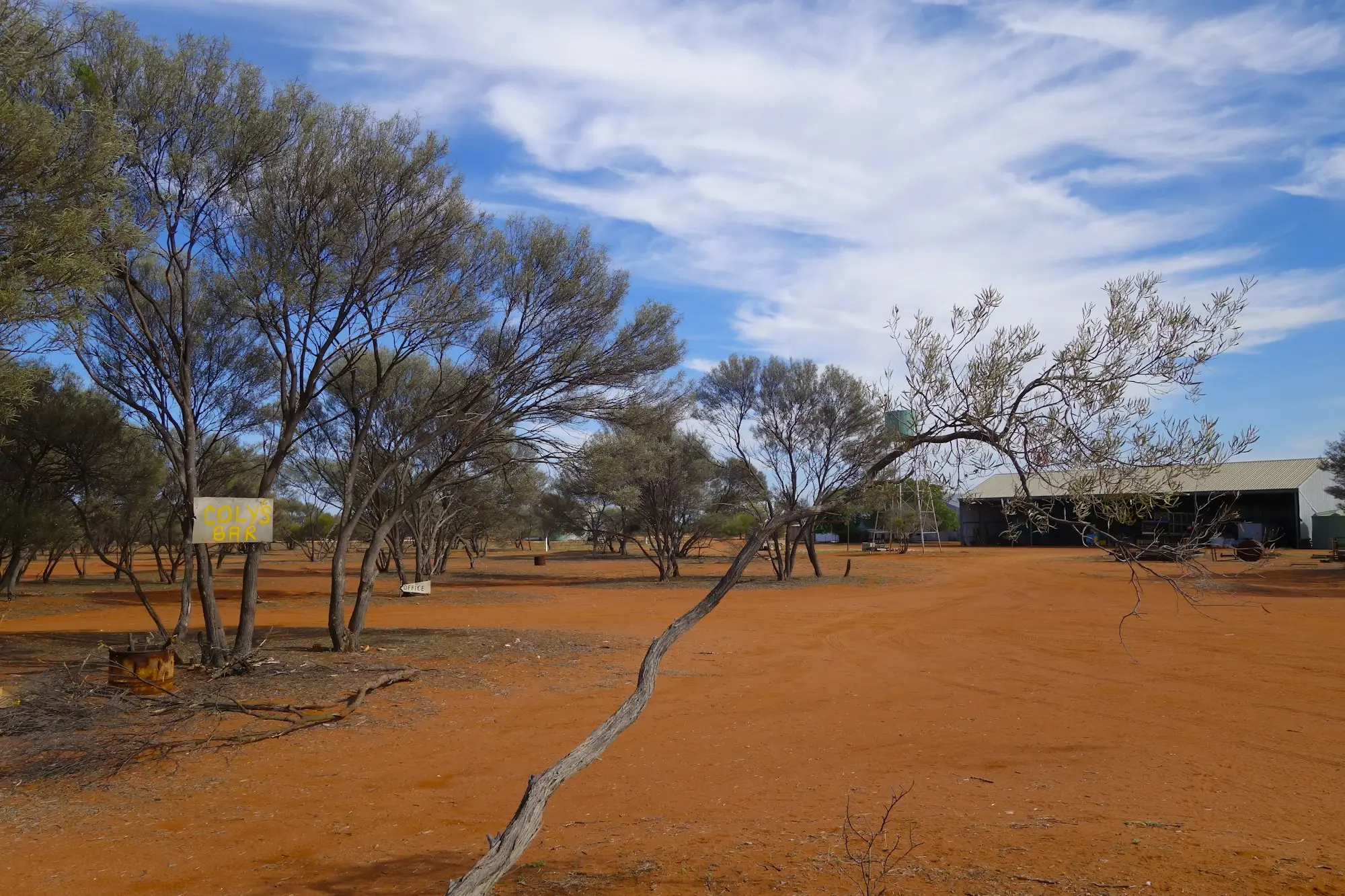 Red-dirt outback station yard with a machinery shed, the kind of property where business owners rely on a full-size pickup for towing