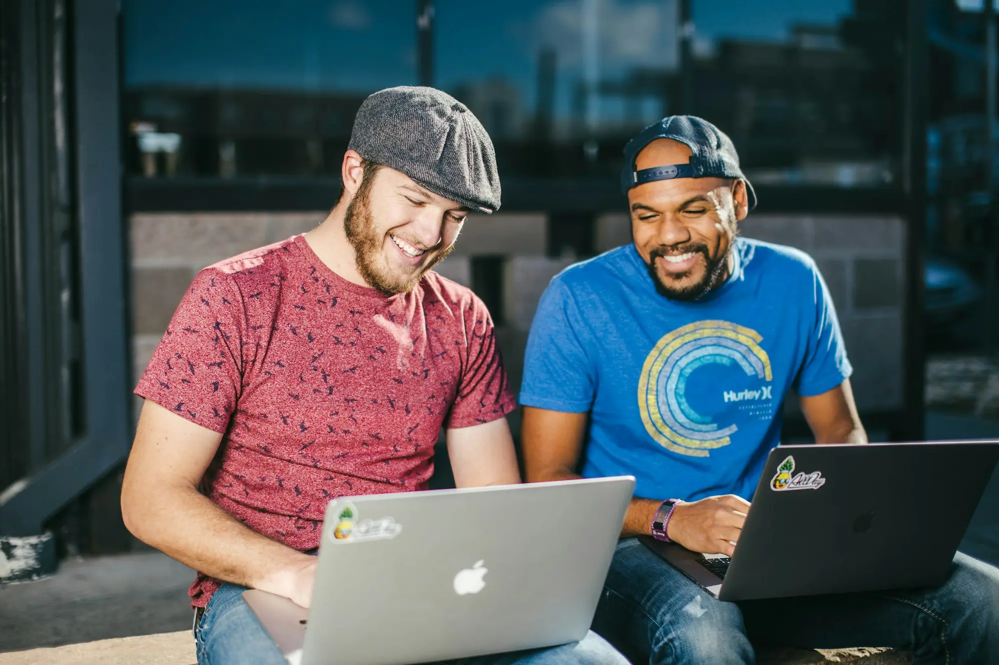 Two contractors working on laptops outside a city office building
