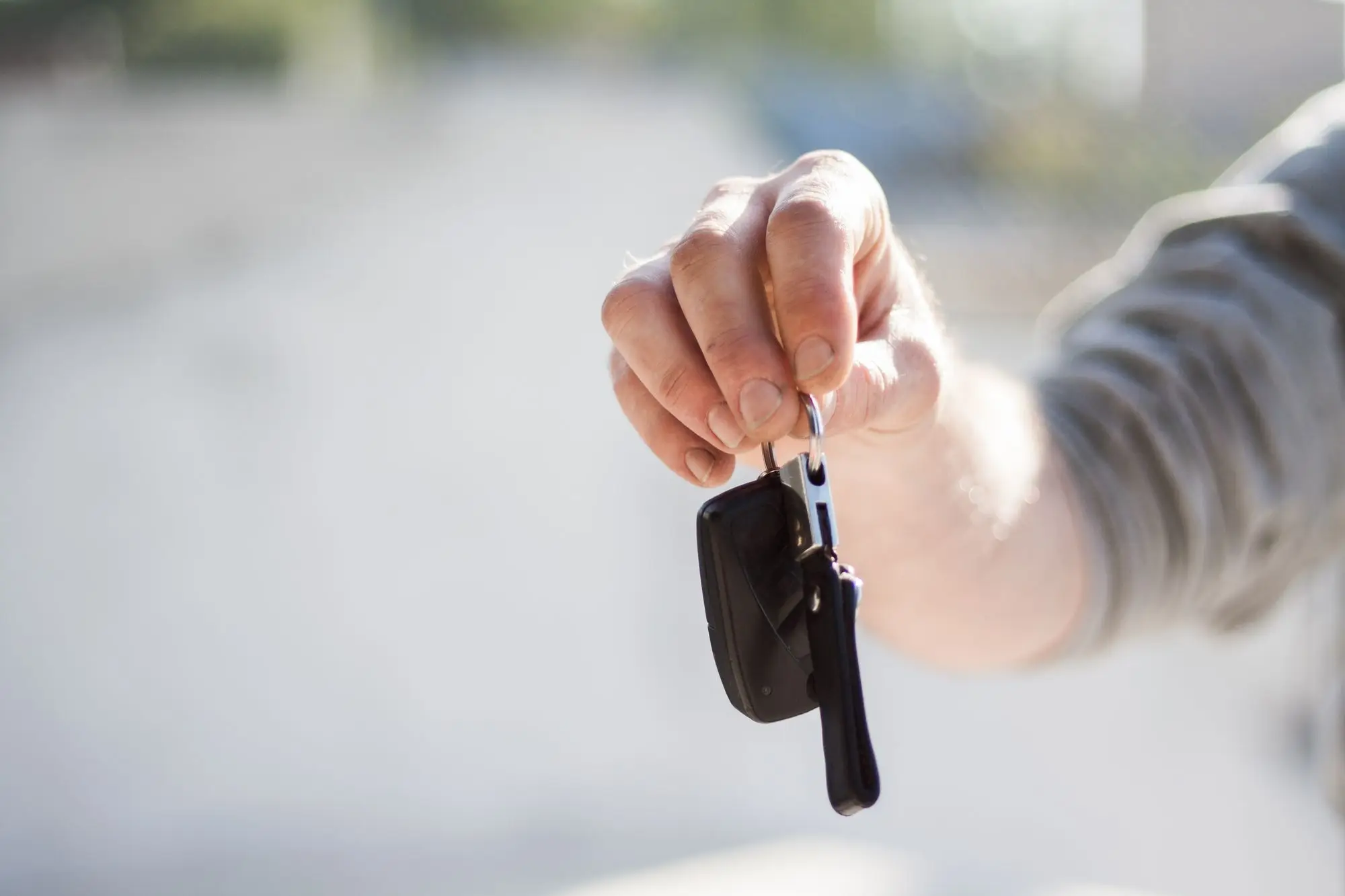 Business owner holding out a set of vehicle keys, ready to hand the work car over to their new company